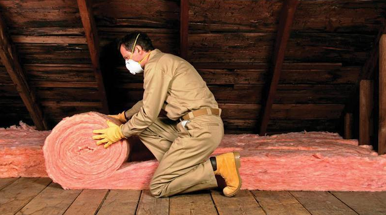 a man in a room with a large roll of attic insulation